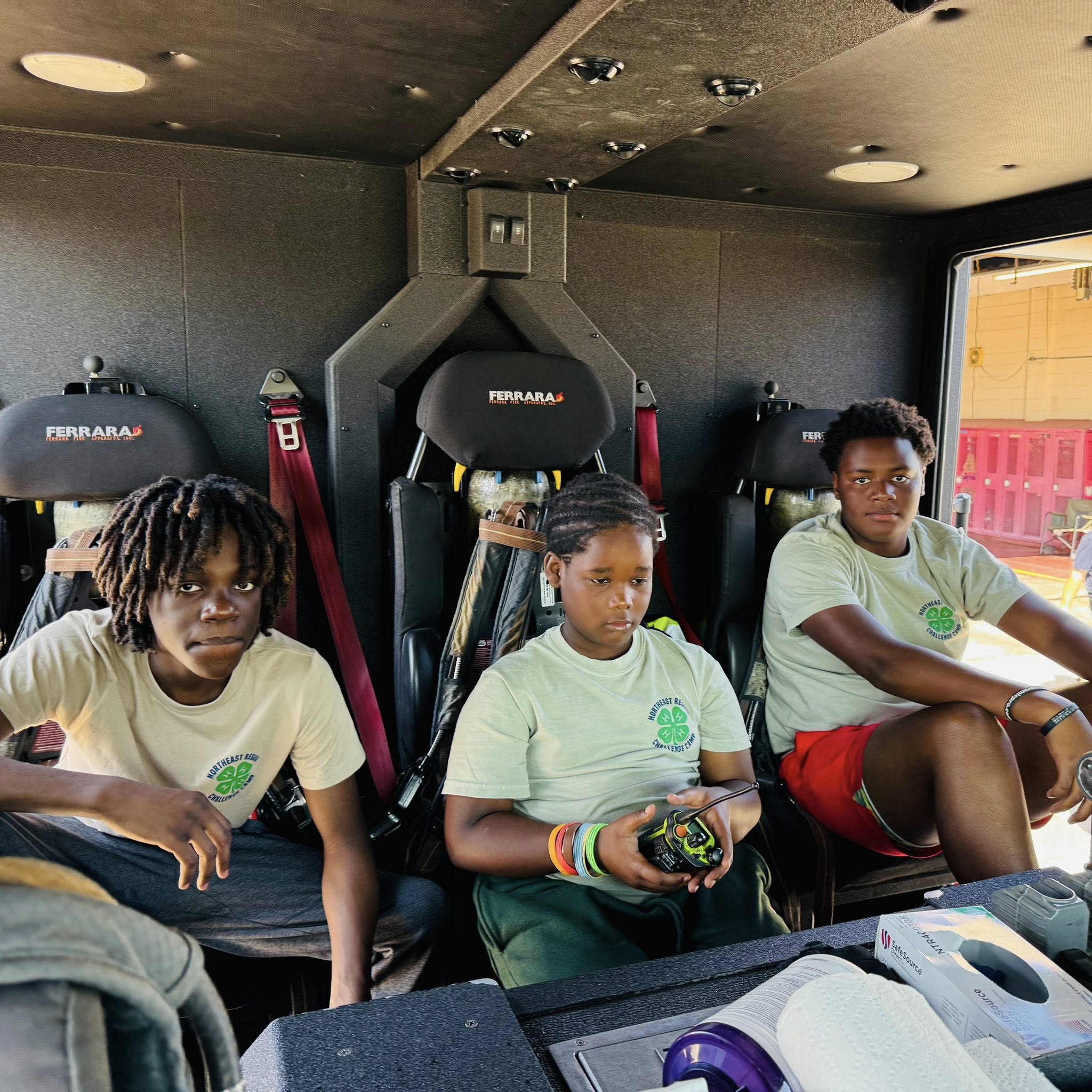 Three boys sitting inside a S.W.A.T. vehicle.